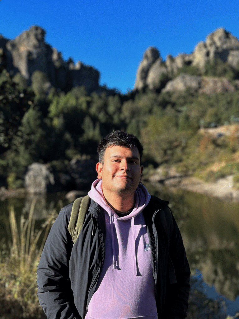 Una fotografía del diseñador de las piezas en medio de un campo en las montañas.