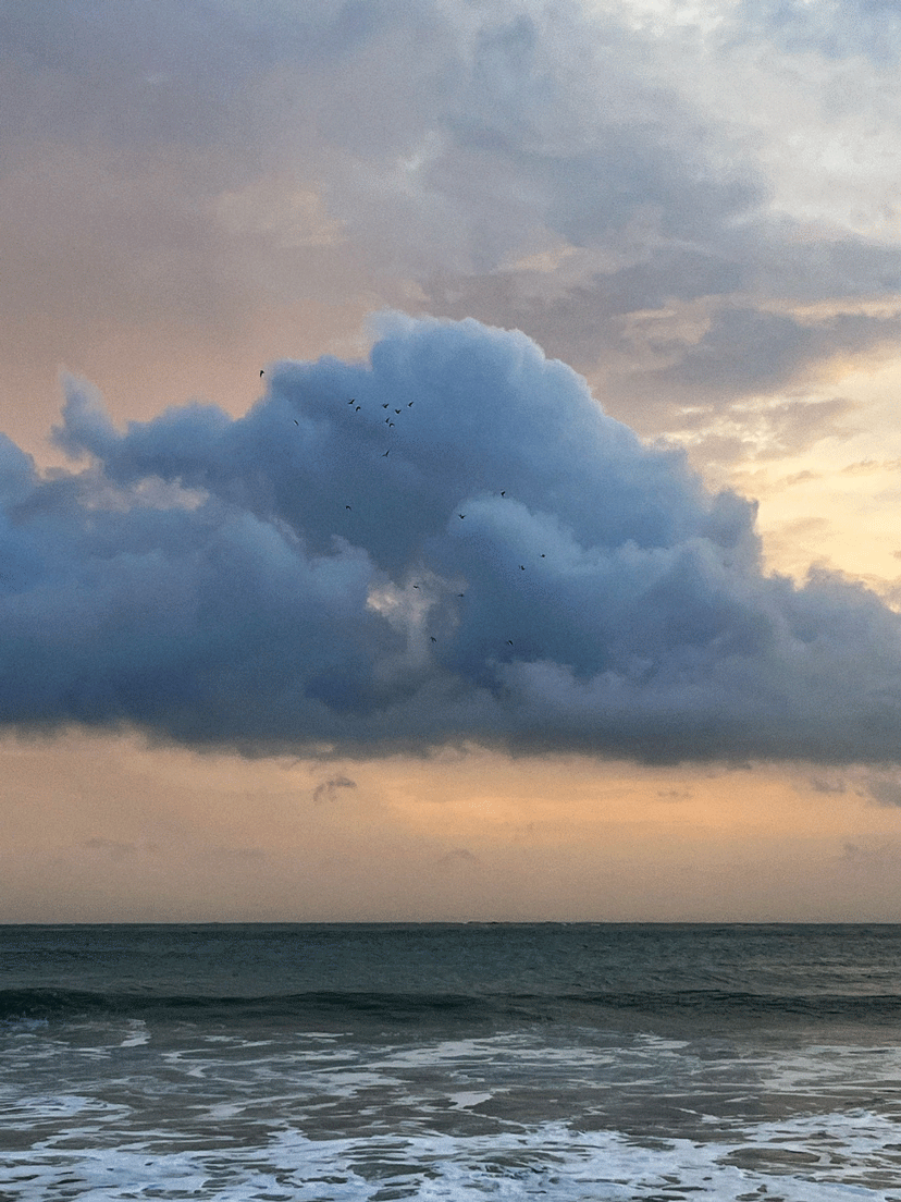 Fotografía de una nube encima del mar al atardecer.