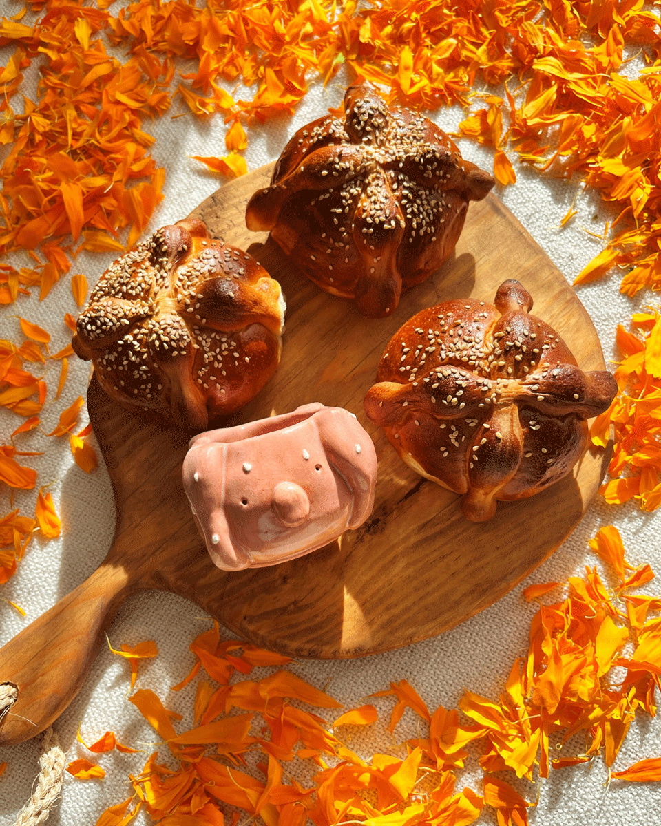 Taza de pan de muerto encima de un montón de flor de cempasúchil.